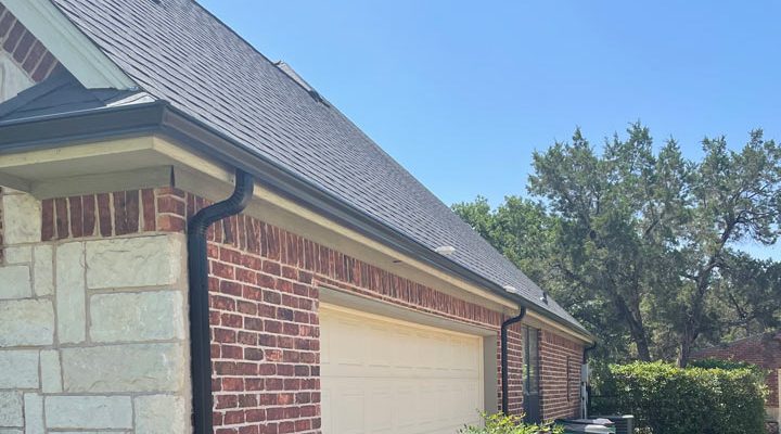 a home with brick outside walls, gutters, downspouts, and a garage