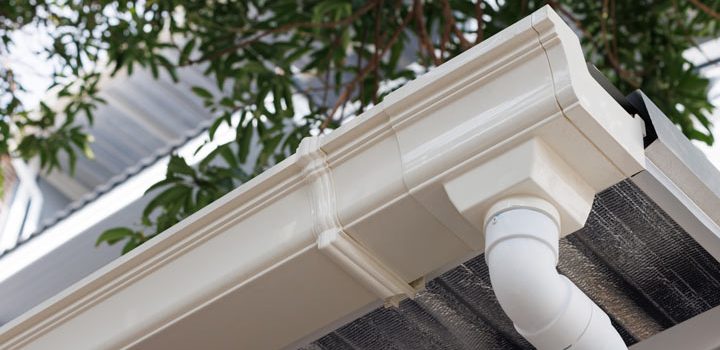 the newly installed gutter in white paint with a white painted downspout